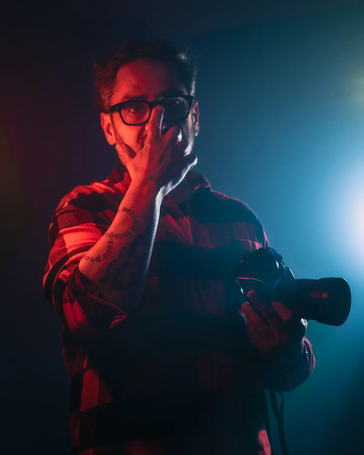 Fotograf mit Kamera in blau und rot beleuchtetem Studio